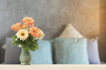 flowers in vase on wooden table with bedroom.