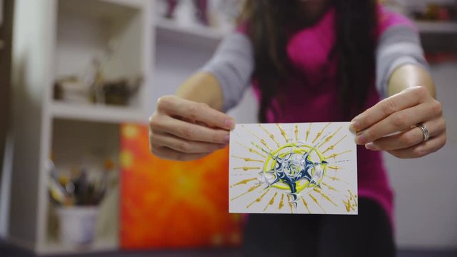 Female artist exhibiting painted picture card in hands 4K