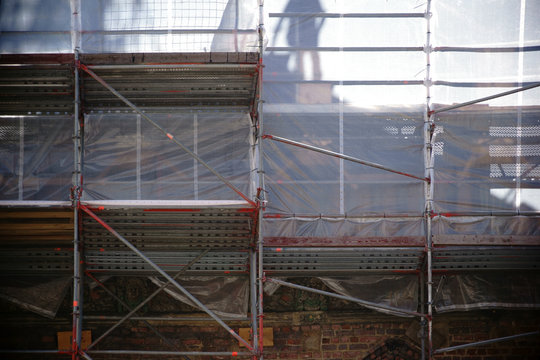 Baustellengerüst  / Die Silhouette und der Schatten eines Bauarbeiters während einer Restauration hinter einem Baugerüst.