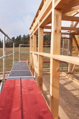 Metal scaffolding around the unfinished house.  Construction of ecological house. Wooden frame of house under construction.Framed New Construction of a House. Timber house in building process
