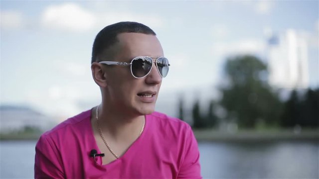 A young man in sunglasses speaking.