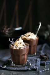 Two glasses of chocolate mousse with lavender topped with whippe