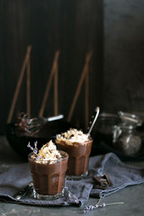 Two glasses of chocolate mousse with lavender topped with whippe