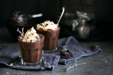 Two glasses of chocolate mousse with lavender topped with whippe