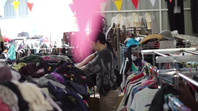 Happy Asian mixed race girl looking for good cheap clothes in sale bazaar