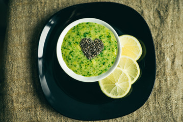 green smoothie with lemon and kiwi fruit on black plate. Burlap texture, Heart of Chia seeds