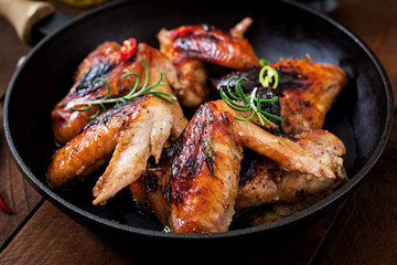 Baked chicken wings in pan on wooden table.