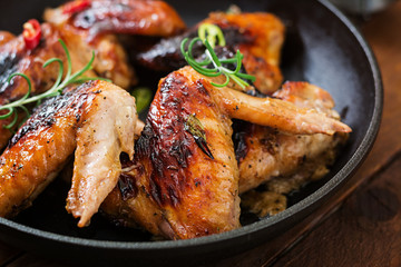 Baked chicken wings in pan on wooden table.