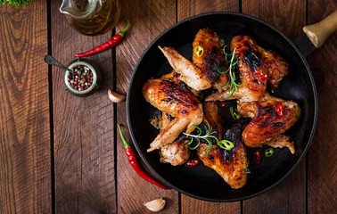 Baked chicken wings in pan on wooden table. Top view