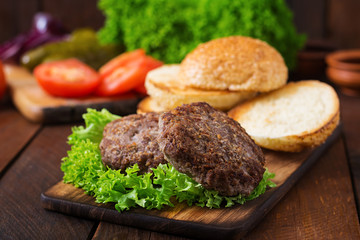 Ingredients for a sandwich - hamburger burger with beef, pickles, tomato and red onion on wooden background.