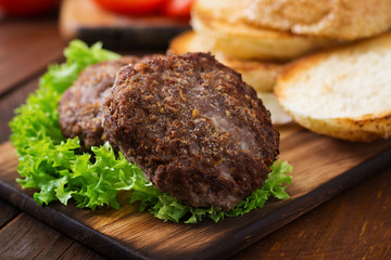 Ingredients for a sandwich - hamburger burger with beef, pickles, tomato and red onion on wooden background.