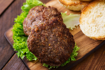 Ingredients for a sandwich - hamburger burger with beef, pickles, tomato and red onion on wooden background.