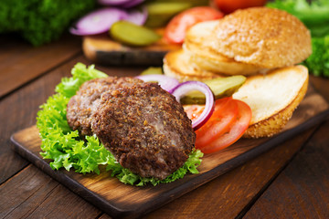 Ingredients for a sandwich - hamburger burger with beef, pickles, tomato and red onion on wooden background.