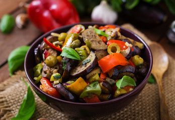 Hot spicy stew eggplant, sweet pepper, olives and capers with basil leaves.