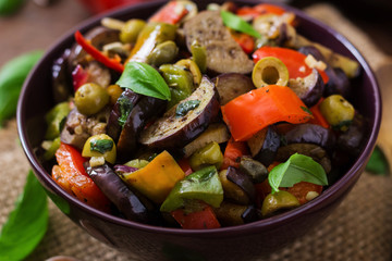 Hot spicy stew eggplant, sweet pepper, olives and capers with basil leaves.