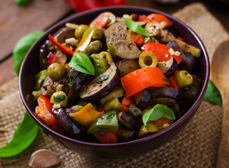 Hot spicy stew eggplant, sweet pepper, olives and capers with basil leaves.
