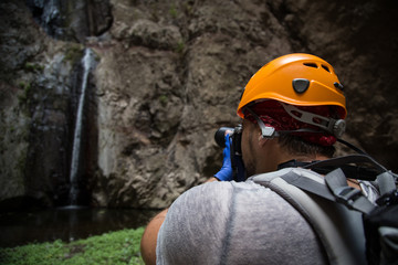 Backpacker man hiking and taking pictures of waterfall in Barranco del Infierno in Tenerife. Canary islands, Spain