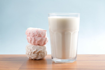 Milk in a glass with a marshmallow on a blue background