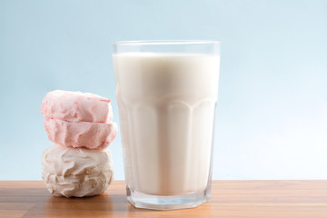 Milk in a glass with a marshmallow on a blue background
