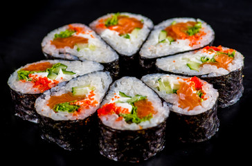 Japanese rolls with fish on a black background