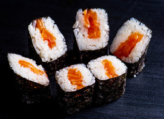 Japanese rolls with fish on a black background
