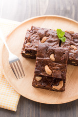 Chocolate brownie with cashew nuts on wooden background.