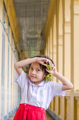 Smiling little schoolgirl in uniform with hair curlers playing a