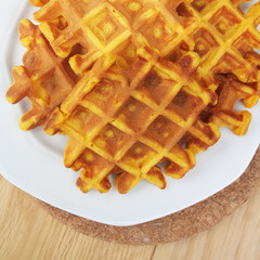 Waffle su piatto bianco su tavolo di legno. Dolce belga.