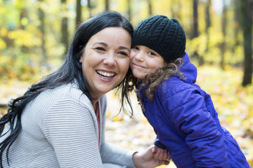 Young mother playing with her daughter in autumn park