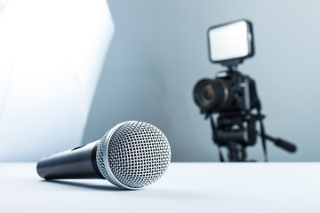 A wireless microphone lying on a white table against the background of the DSLR camera to led light. - obrazy, fototapety, plakaty