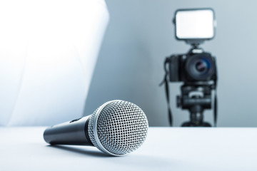 A wireless microphone lying on a studio table against the background of the DSLR camera to led...