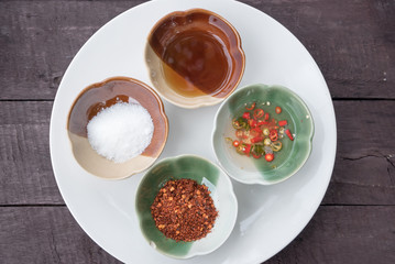 four food seasoning in ceramic, fish sauce, pickled chilli, cayenne pepper, sugar on the wood table