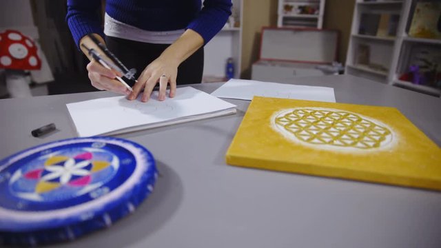 Person drawing mandala with circles on paper 4K