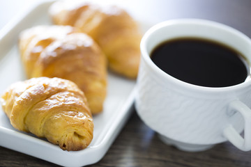 Croissants with coffee on the wooden table. Office workplace