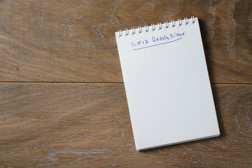 2017 resolutions list on notepad on wood table