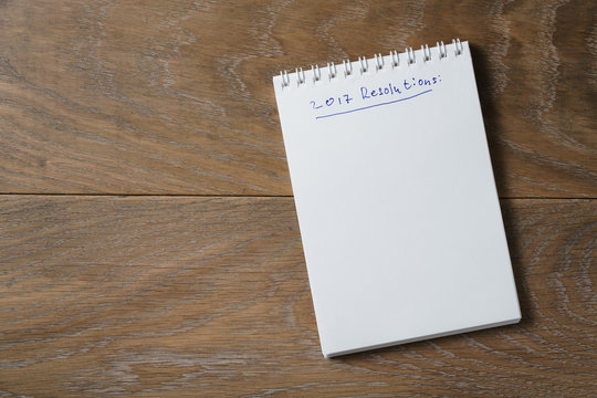 2017 resolutions list on notepad on wood table - Powered by Adobe
