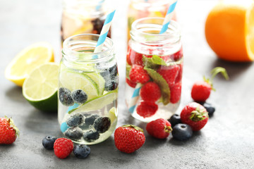 Fototapeta na wymiar Detox water in bottles with berries on wooden table