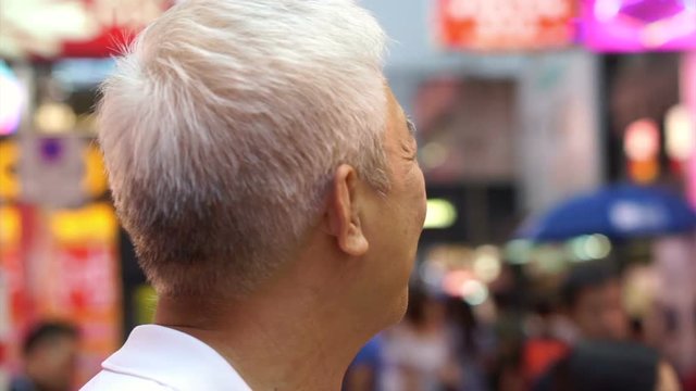 Asian senior man enjoying travel trip at evening out in Mongkok, Hong Kong