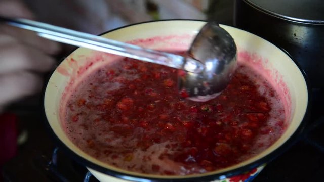Housewife takes foam from strawberry jam