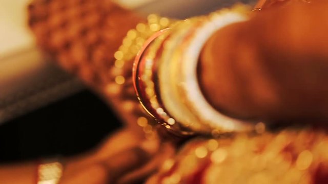 Woman puts golden bracelet on the leg of Hindu bride