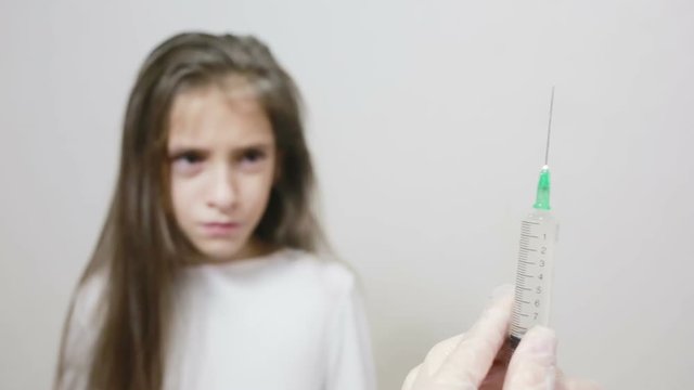 little girl is afraid of the doctor with a syringe. baby cries afraid injection