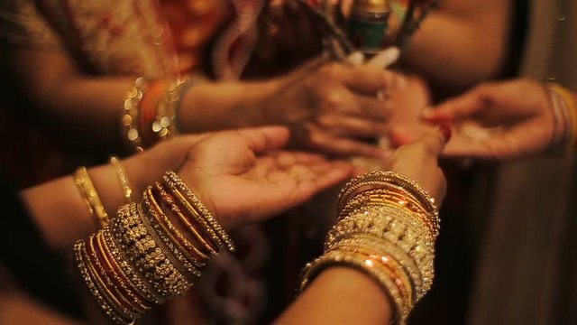 Hindu bride and her parents hold hands in bracelets behind tree branches