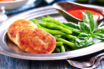 Delicious fish cakes with boiled green beans and tomato sauce