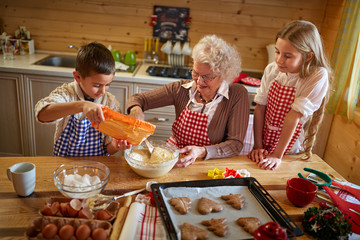 granny making Christmas cookies with kids - obrazy, fototapety, plakaty