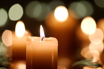 Burning candle with defocused candlelight background