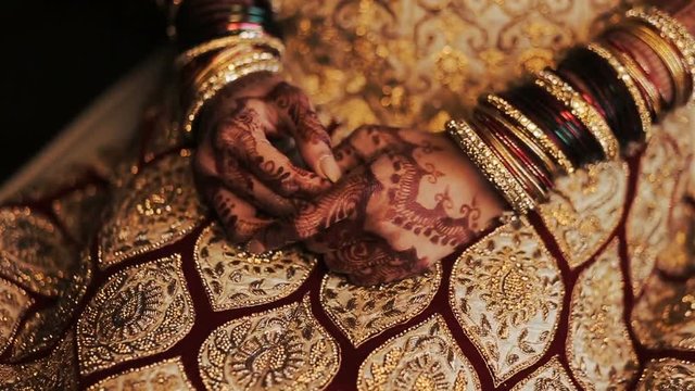 Red and golden bracelets put over the hands of Indian bride