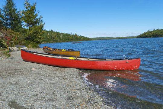 Red canoe on rocky shore  of Moose Lake , Boundary Waters Canoe Area,Minnesota, USA