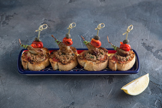 Spanish tapas. Montaditos. Bread slices with tuna, peppers and capers. Typical appetizer.
