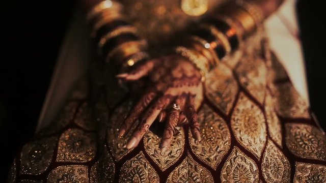 Closeup of Indian bride's hands covered with mehndi and holding a golden necklace