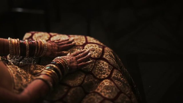 Mehndi covers delicate Indian bride's hands full of bracelets